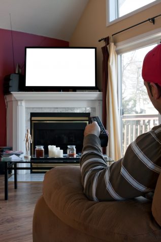 Bored man watches a big screen flat panel TV in his living room.  Screen space on the plasma set has empty white copy space ready for your text or image.