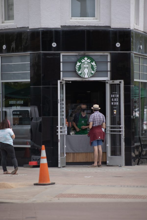 A person orders coffee from Starbucks at the door as others wait around for their coffee orders. Thanks to a variance request approval, restaurants have been cleared to re-open with limited capacity. (Devin Cornelius | Collegian)