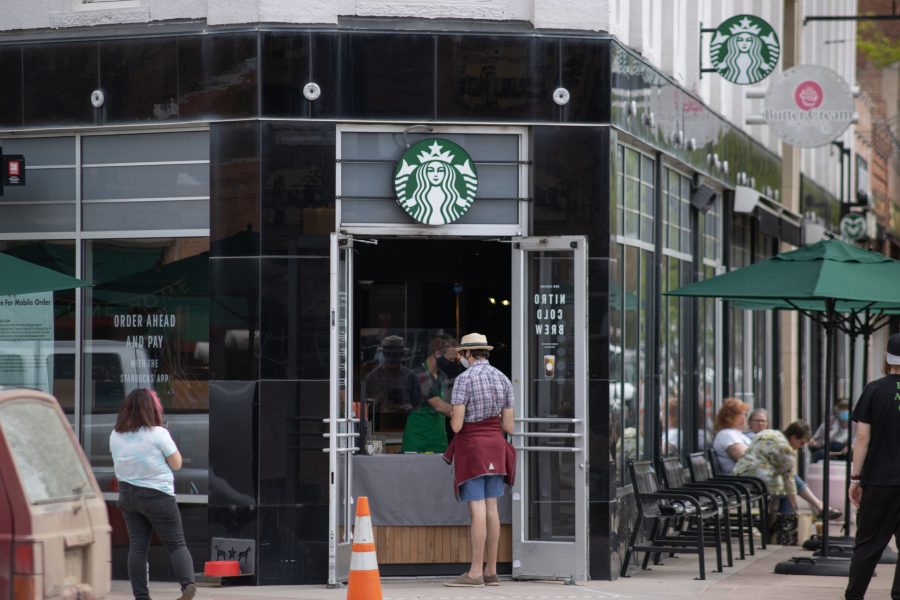 A person orders coffee from Starbucks at the door as others wait around for their coffee orders. Thanks to a variance request approval, restaurants have been cleared to re-open with limited capacity. (Devin Cornelius | Collegian)