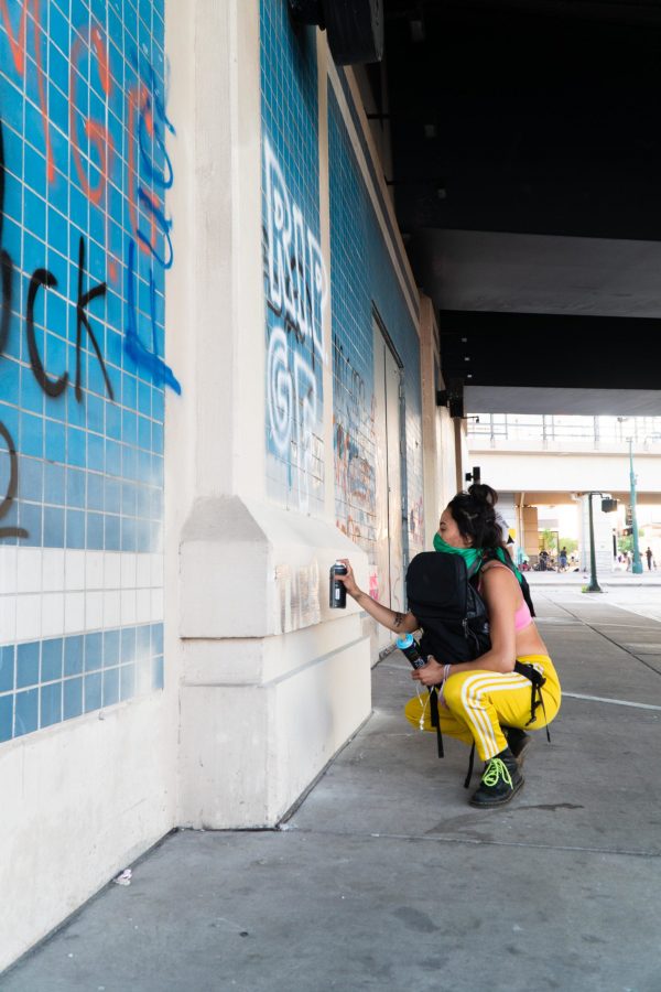 A young woman spray painting under the Highway 55 bridge at Lake Street in Minneapolis in response to the killing of George Floyd, May 28, 2020. (Photo courtesy of Ben Leonard)