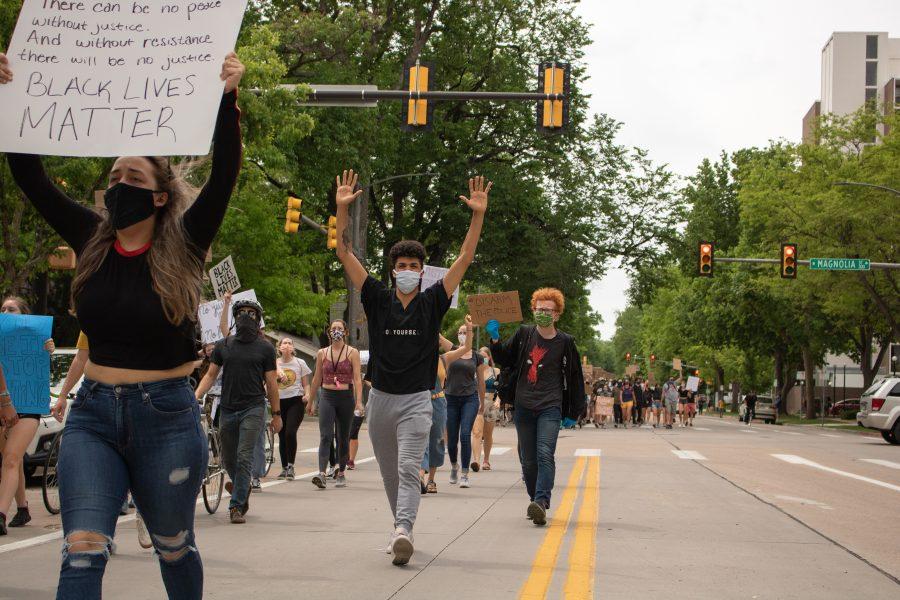 Protesters walk up South Howes Street with their hands up as they head towards Town Hall on June 2. (Devin Cornelius | Collegian)