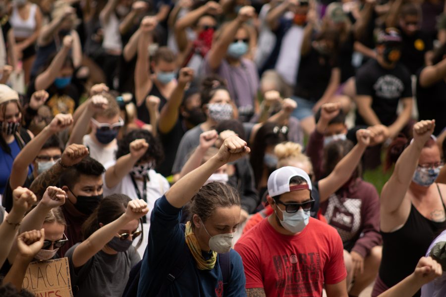Protesters kneel and hold up the Black Power fist while protesting in front of the Administration Building at Colorado State University on June 2. (Devin Cornelius | The Collegian)