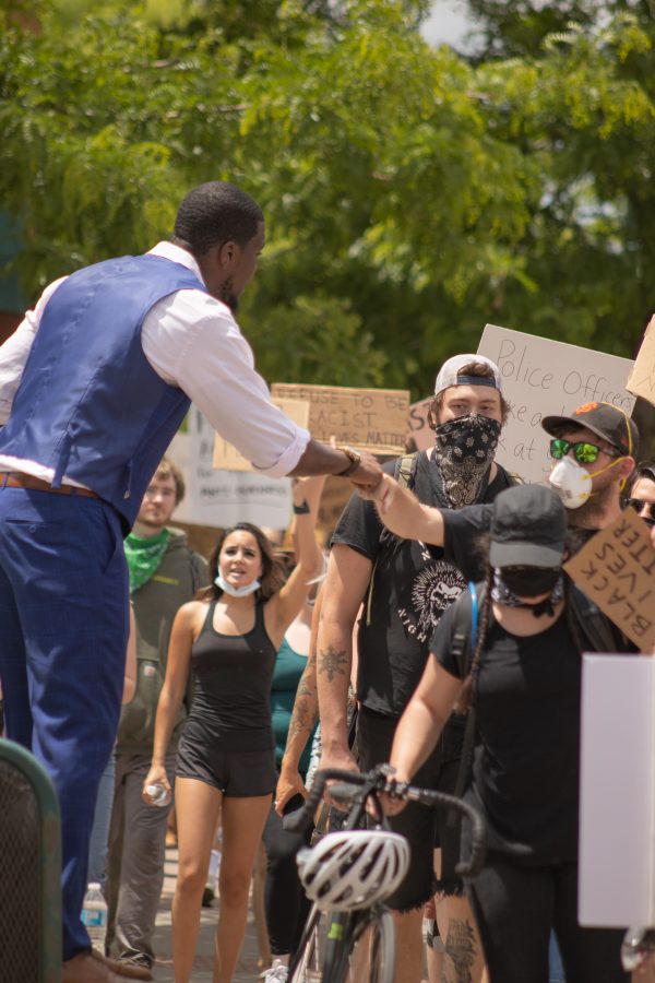 Protesters fist-bump while they march through Old Town to protest police brutality on June 5, 2020. (Devin Cornelius | Collegian)