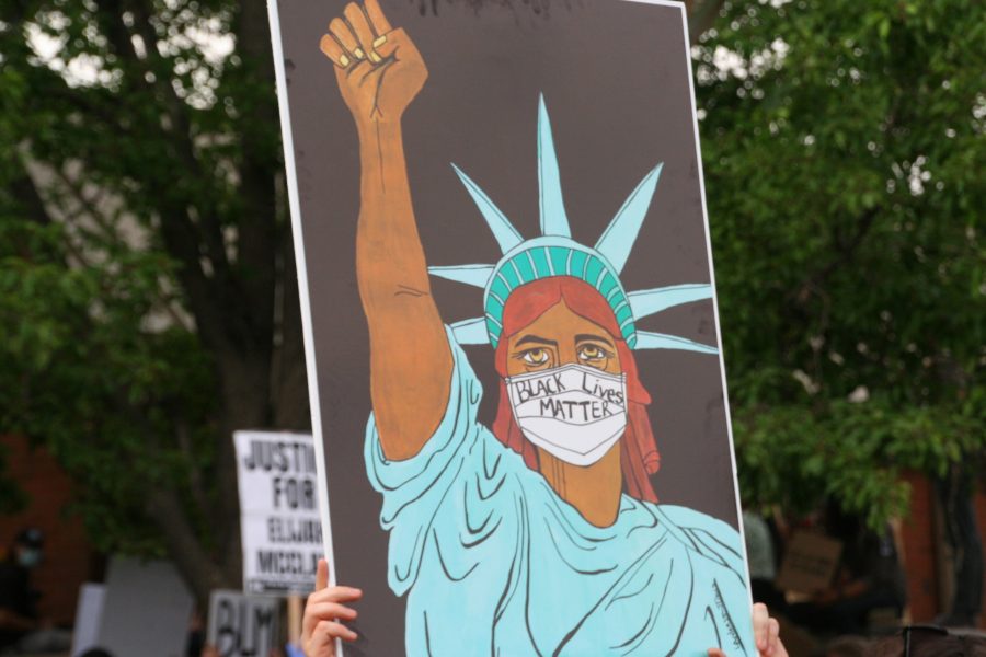 Someone holds up a sign depicting the Statue of Liberty wearing a mask that says Black Lives Matter. Many signs had creative illustrations on them during the protest on June 27. (Katrina Leibee | The Collegian).