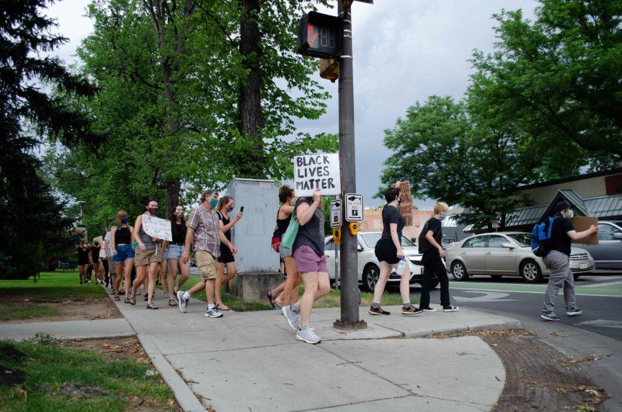 Protestors carry their signs through the streets. They crossed with little regard for the crosswalk signals. (Reed Slater | Collegian)