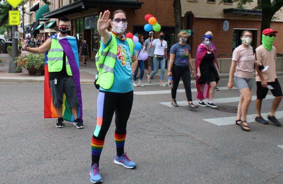 Volunteers watch the street and people march down College Avenue July 17, 2020 for the second annual NoCo Pride March. (Serena Bettis | The Collegian)