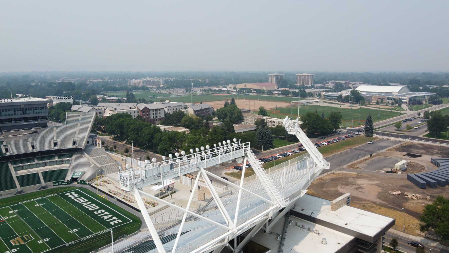 A aerial photo of Canvas Stadium and the rest of the Colorado State University campus with a skyline covered by smog.