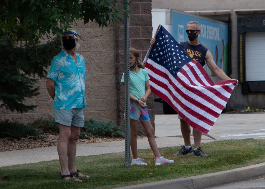 Man holds up an American flag as he watches the end of the memorial procession of emergency vehicles drive down Drake Road for Larimer County Department of Natural Resources Ranger, veteran and Colorado State University alum Brendan Unitt Aug. 28. (Anna von Pechmann | The Collegian) 