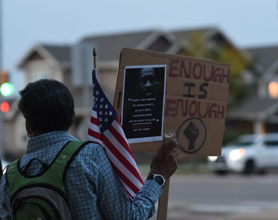 A man holds a sign calling for racial justice at the Rally for Justice. (Tri Duong | The Collegian)
