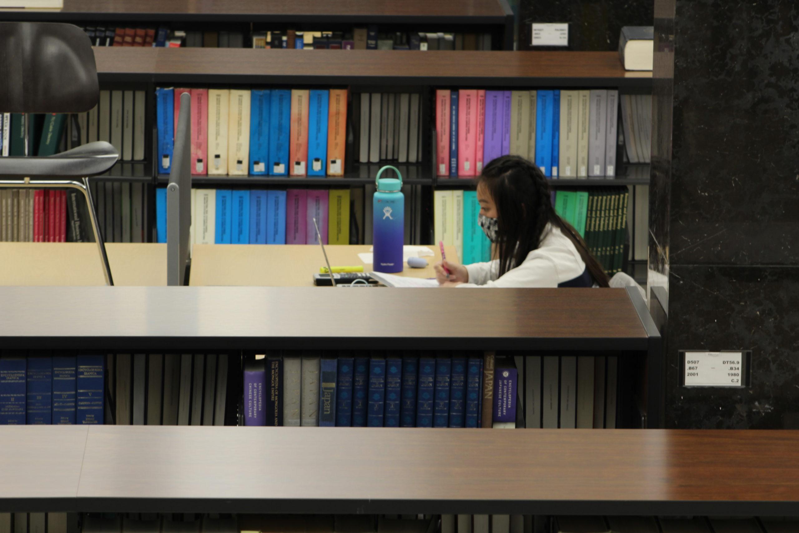 girl studies at library among books