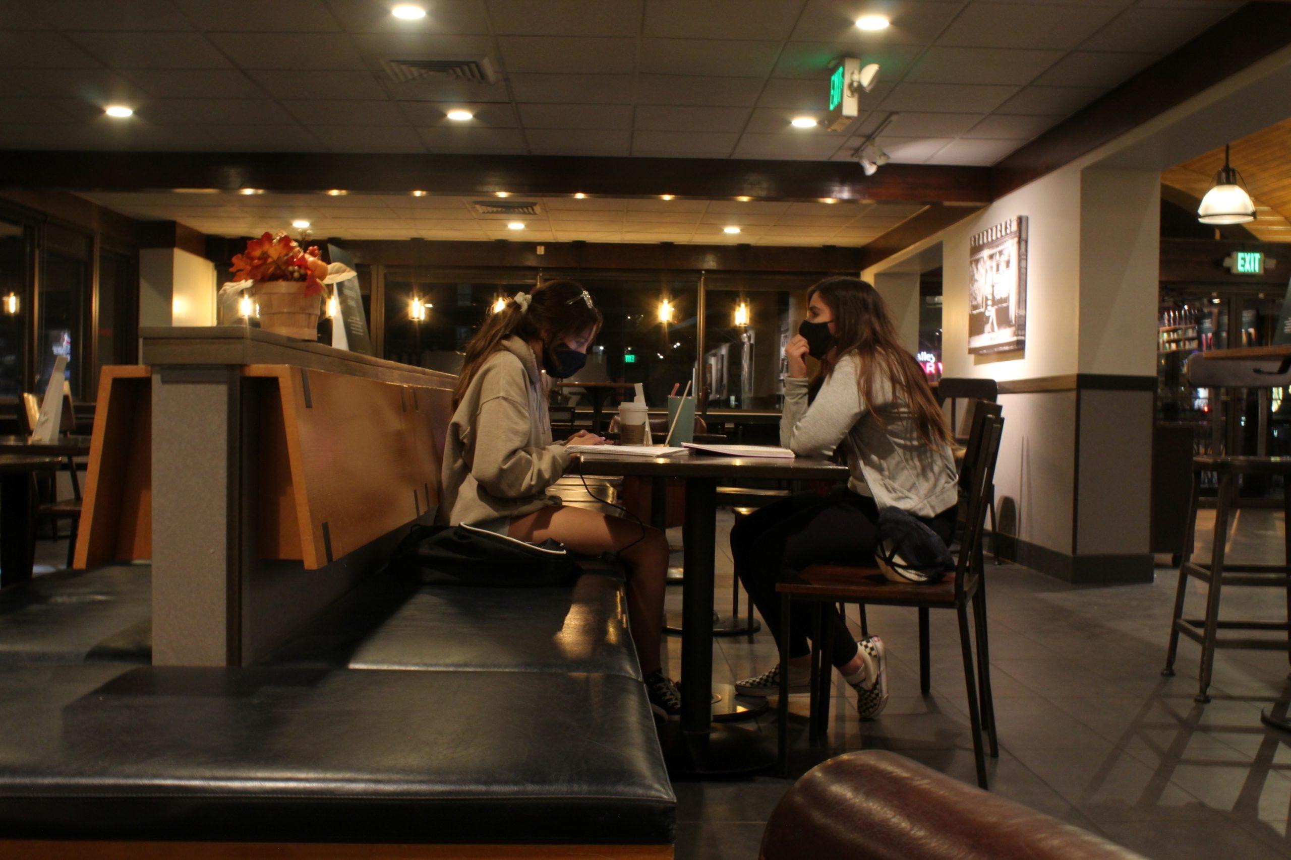 two women sit across from each other at a booth