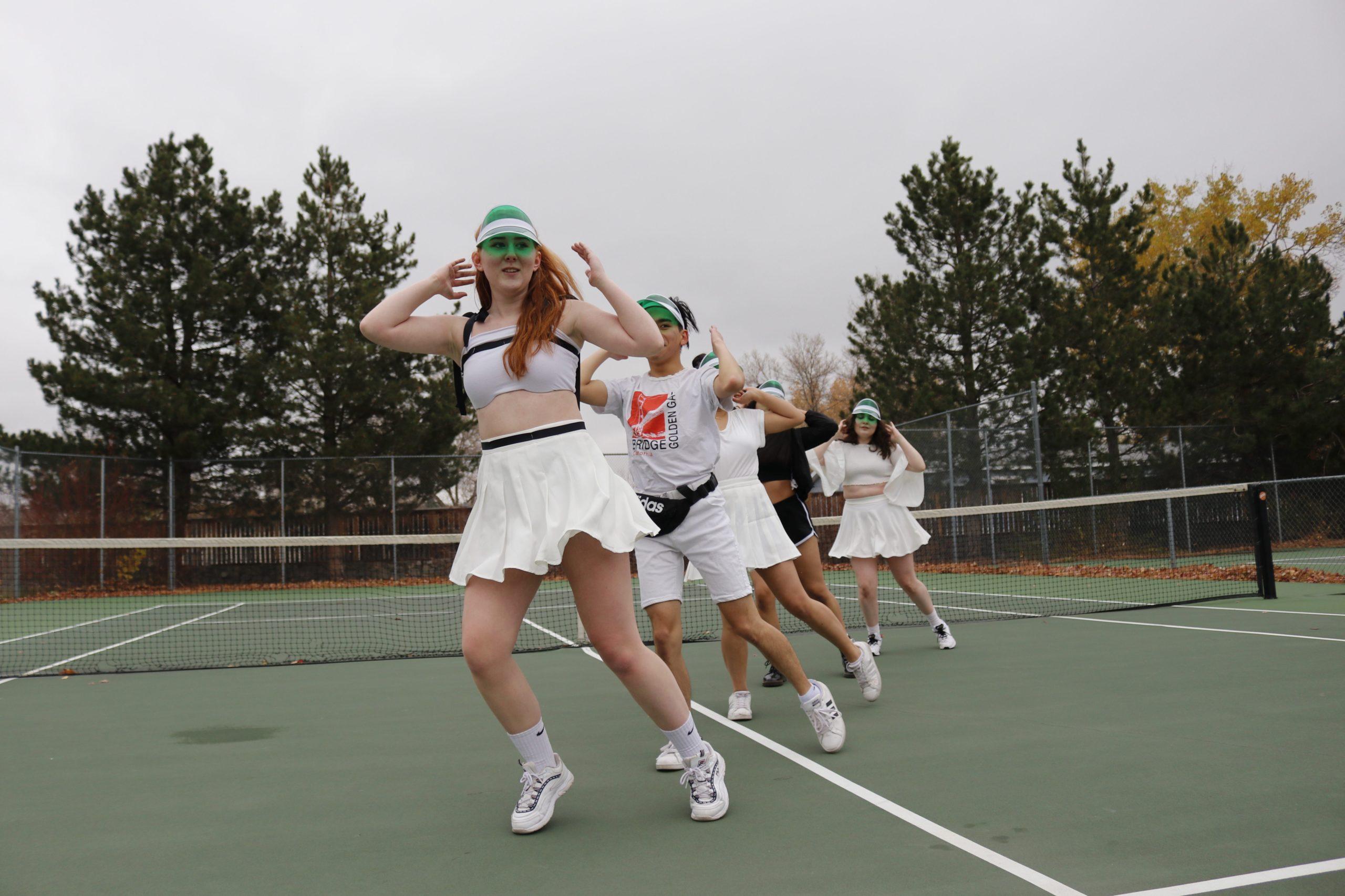 dancers perform on a tennis court
