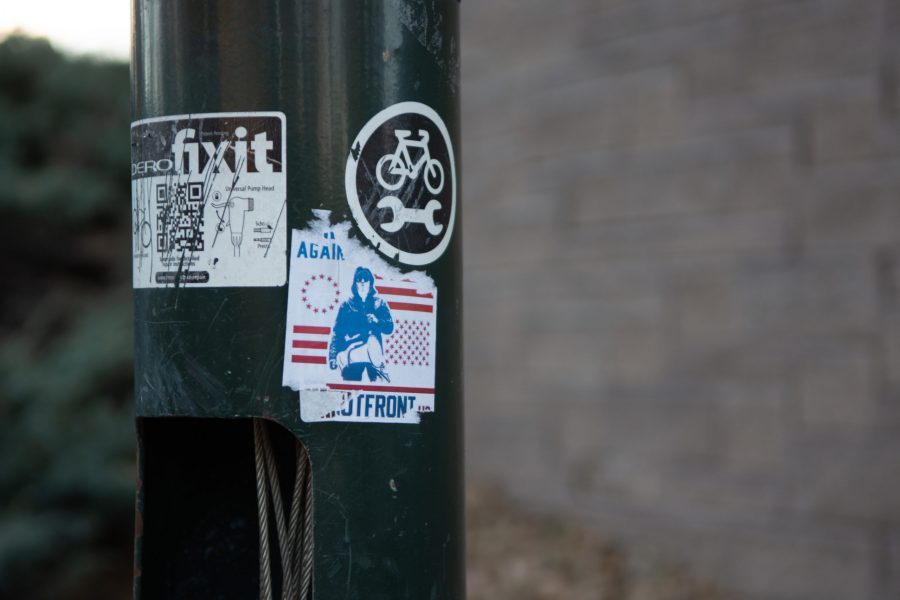 A partially scratched off Patriot Front sticker on a bike work stand next to the tunnel under Prospect Road outside the University Center for the Arts Nov. 16. The Southern Poverty Law Center calls Patriot Front a “white nationalist hate group.” (Matt Tackett | The Collegian)