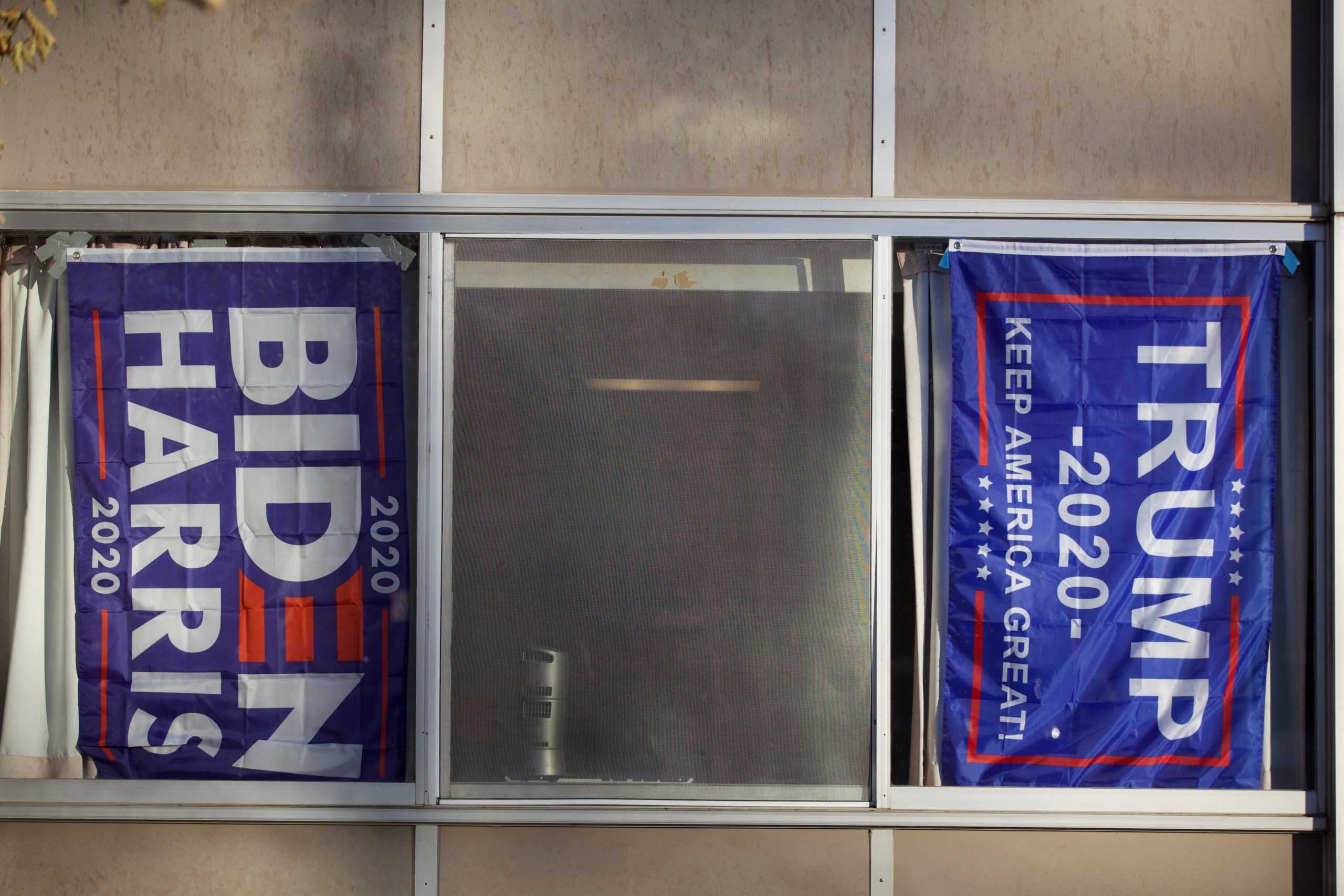 a Biden flag and a Trump flag in a window