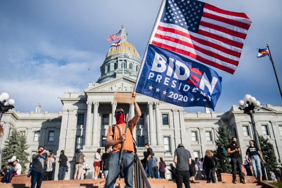 A Joe Biden supporter stands on the steps to the Colorado State Capitol in Denver, waving an American flag and a Biden campaign flag hours after Biden was declared the president-elect Nov. 7. (Lucy Morantz | The Collegian)