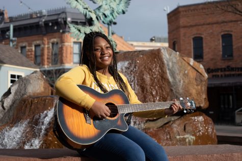 Local singer songwriter Julia Kirkwood looks at her parents as she plays guitar in Old Town square, Feb. 6. (Anna von Pechmann | The Collegian)