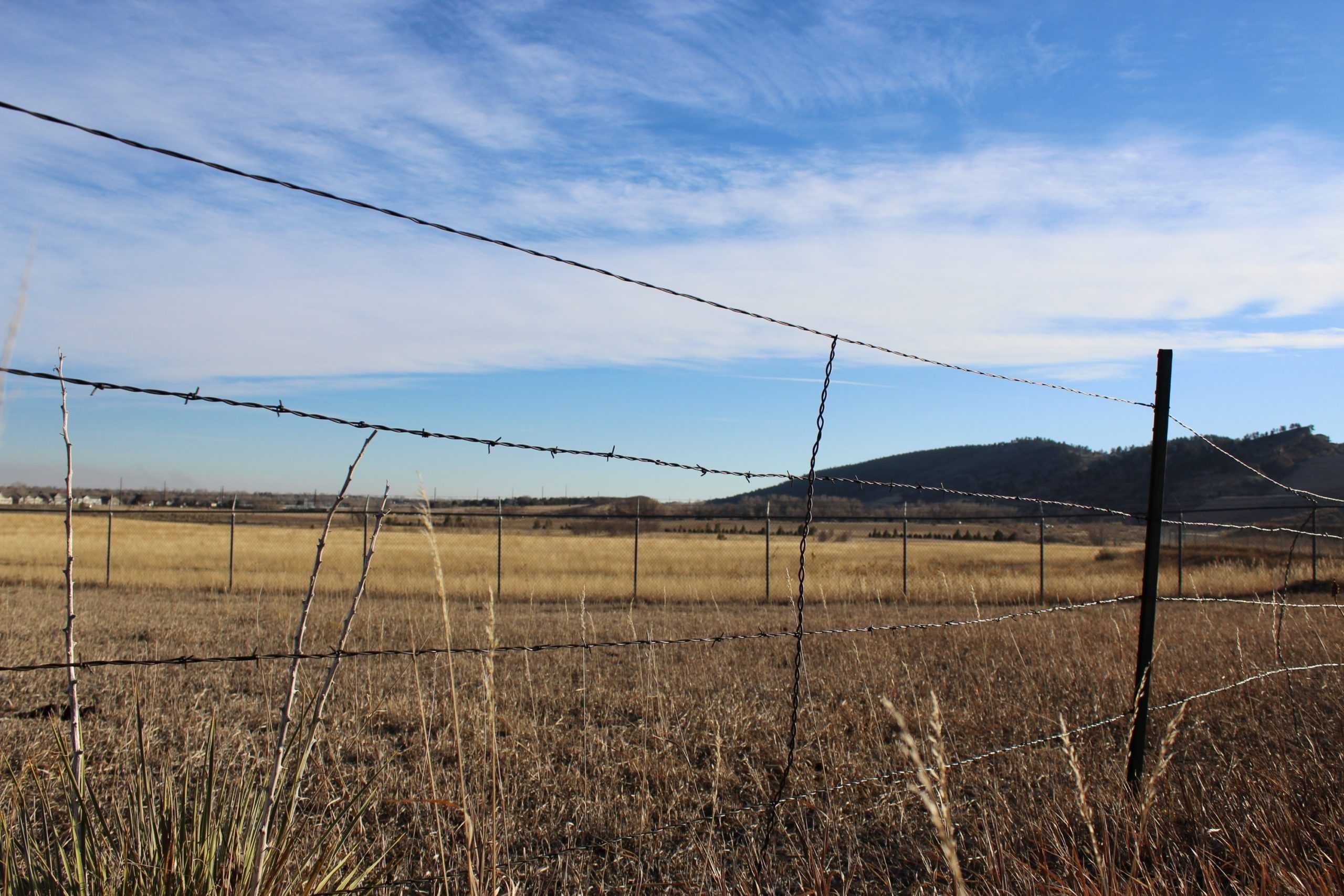 barbed-wire fence in front of the Hughes Stadium development site