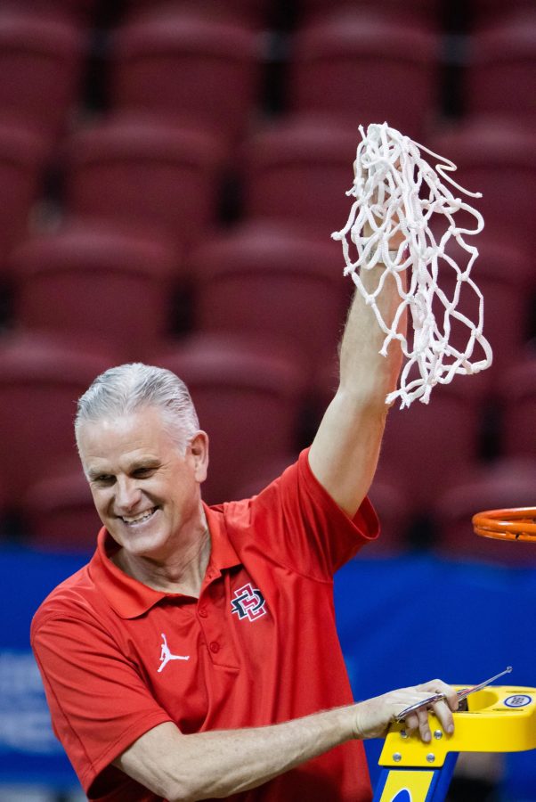 Coach Brian Dutcher holds up the game net after his San Diego State Aztecs defeat the Utah State Aggies in the Air Force Reserve Mountain West tournament final and advance to the NCAA tournament. (Devin Cornelius | The Collegian) 