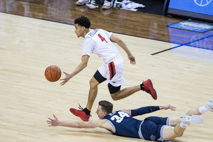 Trey Pulliam (4) scoops up the ball on a fast break while his opponent Justin Bean (34) falls trying to stop him, during the Air Force Reserve Mountain West men's basketball tournament in Las Vegas Nevada. San Diego State University defeats Utah State University 68-57 and become the Mountain West champions. (Devin Cornelius | The Collegian) 