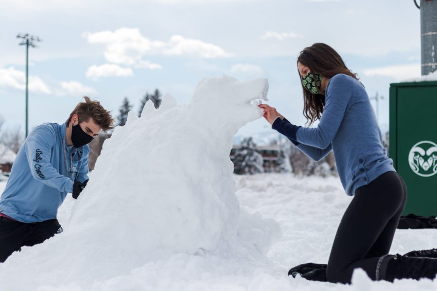 Sean Malley and Madeline Hoffman create a snow sculpture on Colorado State Universitys Intramural Fields during a snow day March 5. Malley said the snowball fight occurring during their sculpting, seemed like just a mess. (Michael Marquardt | The Collegian)