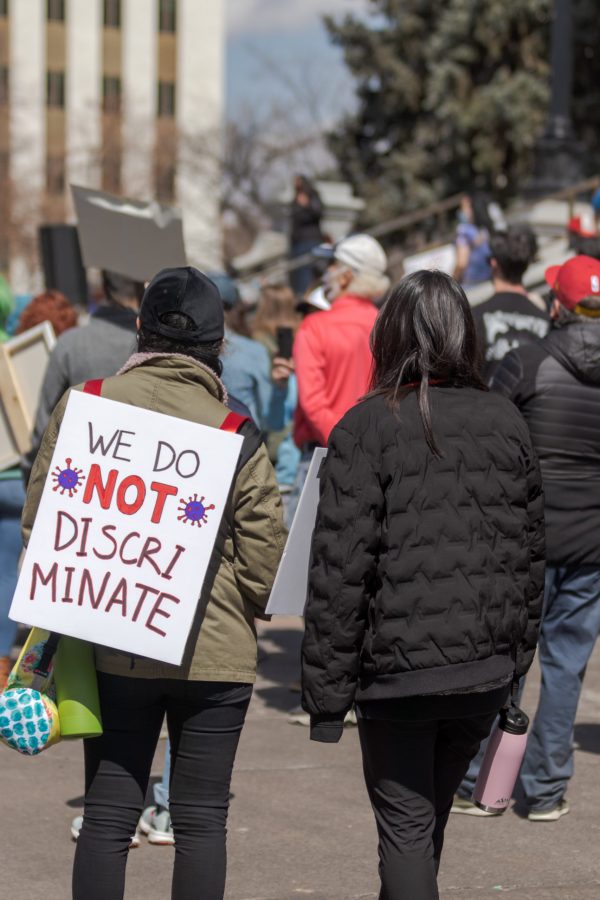 A protester stands with a sign outside the Colorado State Capitol March 27. The protest featured speeches, poetry, and music from the Asian-American and Pacific Islander community. (Michael Marquardt | The Collegian)