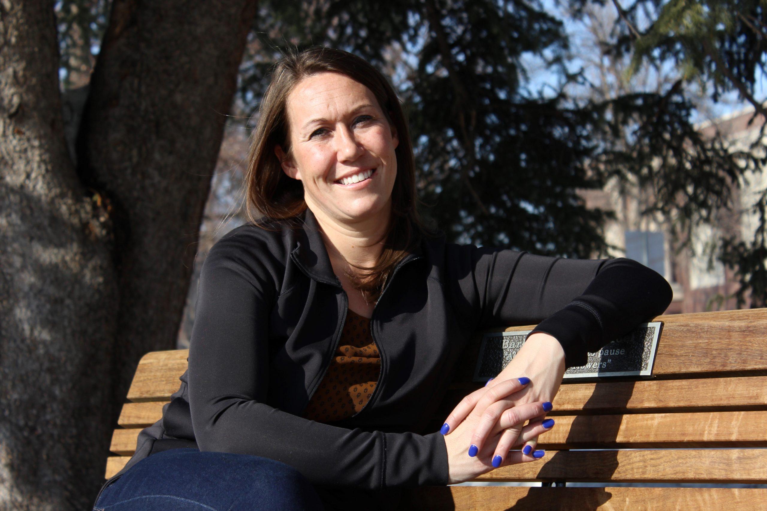 sitting portrait of Jessica Dyrdahl on the bench near the Gazebo outside the University Center of the Arts