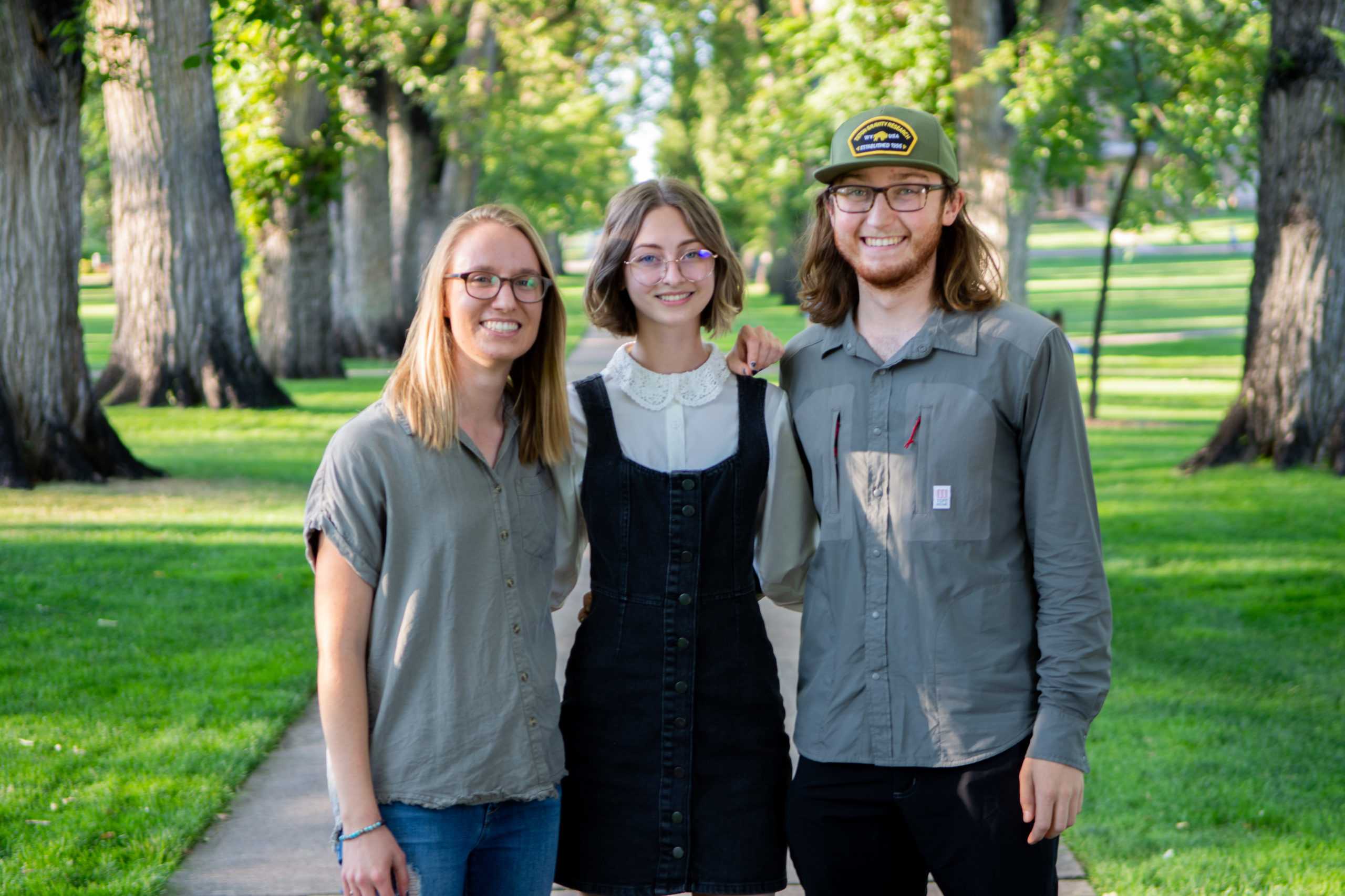 abby, lauryn and matt stand together on the oval with trees in the background