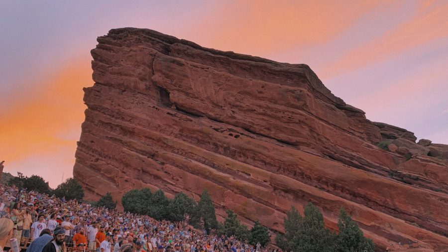 A tie-dyed crowd dances as a sunset illuminates the sky over Red Rocks Amphitheatre on June 8th, 2021 (Dylan Tusinski | The Collegian)