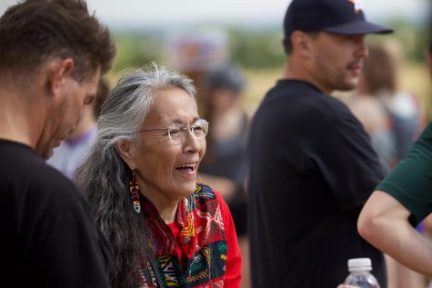 Christinia Eala, an activist for Native American rights, talks with other demonstrators at the A biker at the Maxwell Natural Area Aug. 22 passes signs placed by the Intertribal Alliance for Right Relations. Demonstrators and activists were at the trailhead to explain the history of the Hughes land and their hope for it to be used as a gathering place for Indigenous people. (Ryan Schmidt | The Collegian) on Aug. 22. Elea and other activists envision the land that used to be the site for Hughes Stadium serving as a gathering place for Indigenous people, but Colorado State University is currently planning to develop housing and other facilities on the land. (Ryan Schmidt | The Collegian)