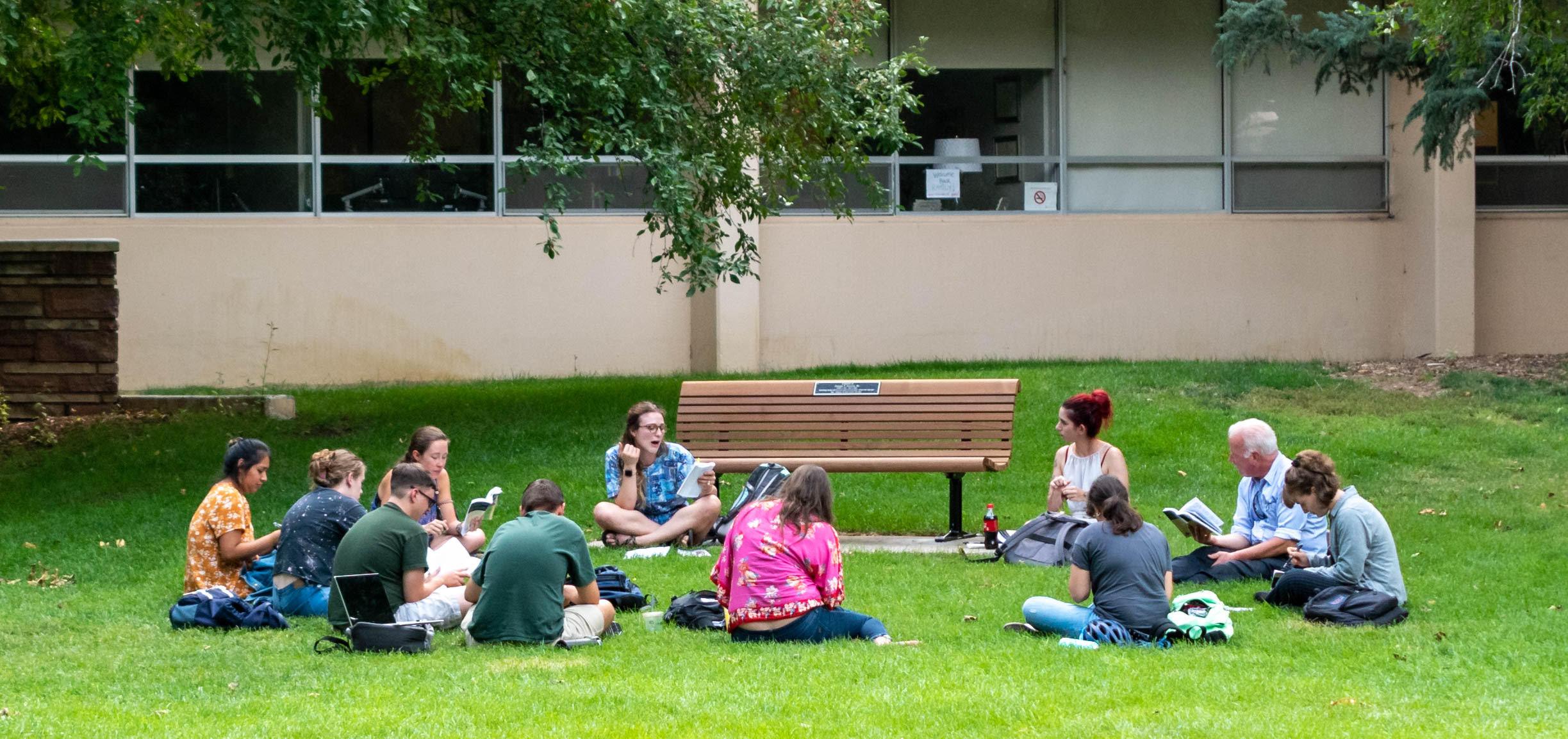 students sit and talk in a circle outside