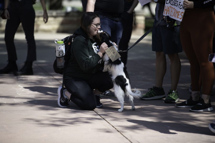 Natalie Buchholz gets kisses from a dog during a Call Out Colorado State University protest on the CSU campus Plaza Sept. 17. (Garrett Mogel | The Collegian)