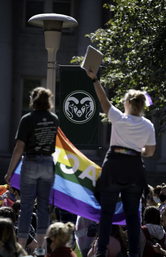 Community members hold a pride flag reading “peace” in front of the Colorado State University Administrative Building during a Call Out CSU protest Sept. 17. (Garrett Mogel | The Collegian)