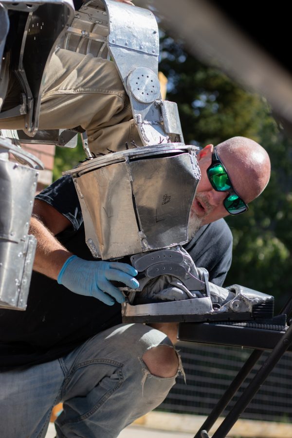 Robin Edmiston carefully assembles the Mark I Iron Man suit around his son, the designer and manufacturer, Dylan Edmiston Sept. 19. The suit of metal requires a second pair of hands to build around the pilot. (Grayson Reed | The Collegian)