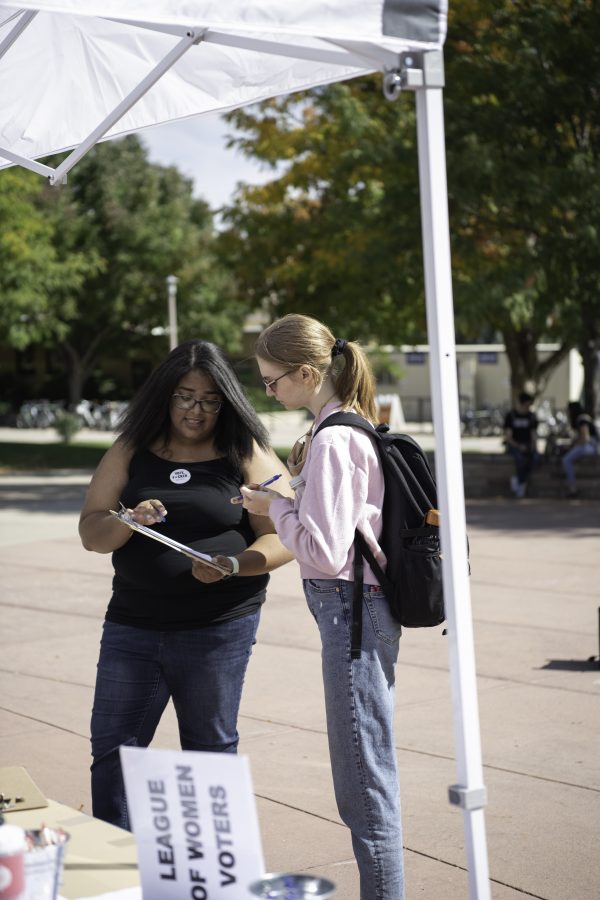 Elijah Sandoval goes through a voter registration form with a Colorado State University Student. Sandoval is part of both New Era Colorado and The Associated Students of Colorado State University who are out on the CSU Plaza to help students register to vote. Sandoval stated "...being that I am a black woman, a lot of black voters, or black voices aren't represented that much, so for me, it's getting the black voice out there as well." Sept. 28. (Garrett Mogel | The Collegian) 
