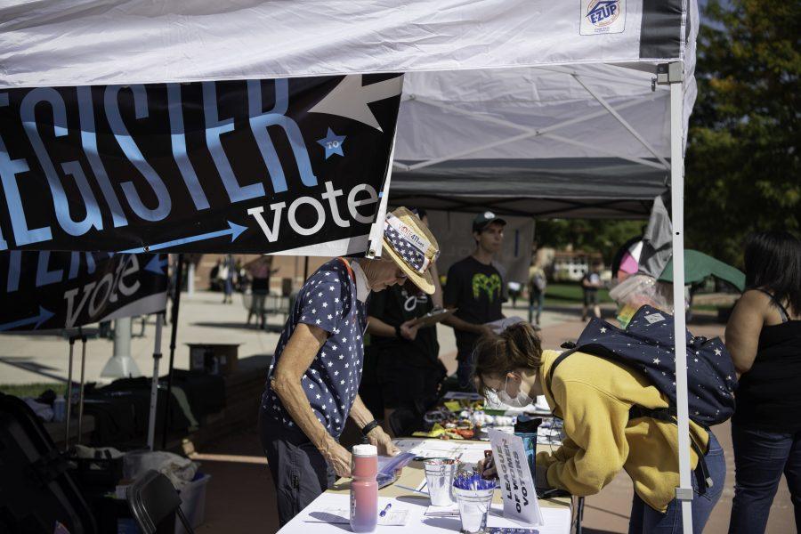 Pat Burger helps a Colorado State University student with Voter registration. Burger is part of the League of Women Voters who were set up alongside The Associated Students of Colorado State University and New Era Colorado on the CSU Plaza to help students register to vote Sept. 28. (Garrett Mogel | The Collegian) 
