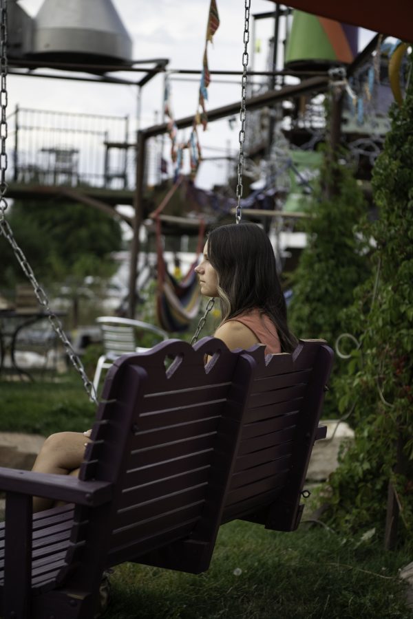 Person sits on a swing bench watching the live music prepare for their show. 