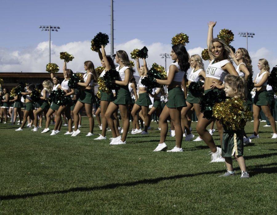 Elliana Joaquin cheers alongside the Colorado State University Cheer team on the Intermural fields in front of parents and students during the homecoming events. Joaquin comes from a long line of CSU Cheerleaders Oct. 9. (Garrett Mogel | The Collegian)