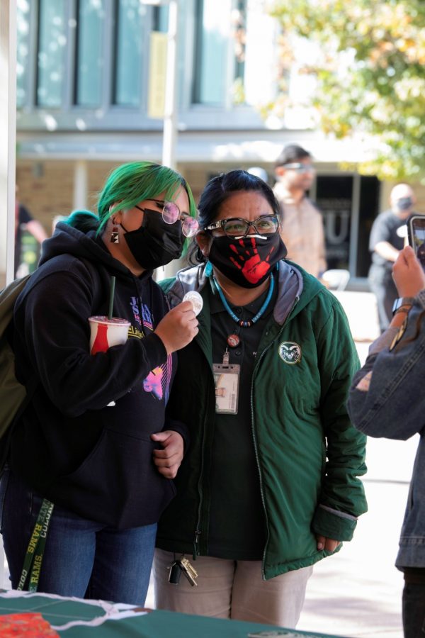 Beverly Morgan, of the Navajo and Zuni tribes, stands next to a Colorado State University student on the Plaza in front of a Indigenous Peoples’ Day booth Oct. 11. (Garrett Mogel | The Collegian)
