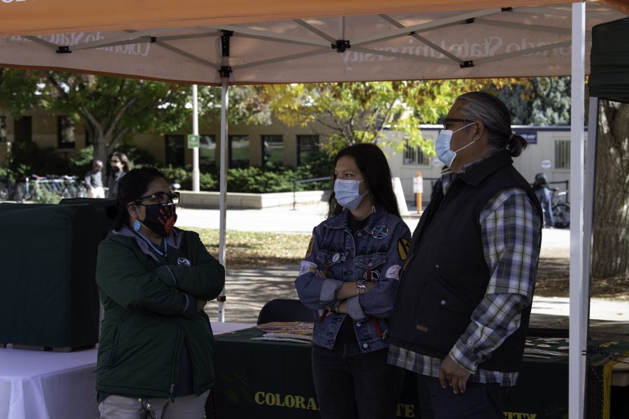 Beverly Morgan of the Navajo and Zuni tribes, Rasa Humeyumptewa of the Hopi tribe, and Ty Smith stand in front of the Indigenous Peoples’ Day booth on the Colorado State University Plaza Oct. 11. (Garrett Mogel | The Collegian)