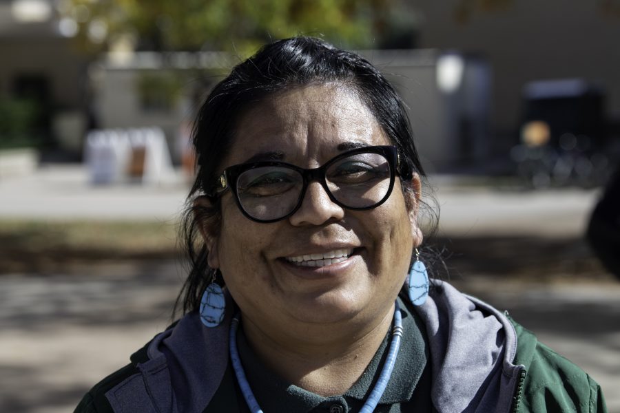 Beverly Morgan of the Navajo and Zuni tribes smiles for the camera in front of the Indigenous Peoples’ Day booth on the Colorado State University Plaza. Morgan stated, “It’s a proud day being native today.” Oct. 11. (Garrett Mogel | The Collegian)
