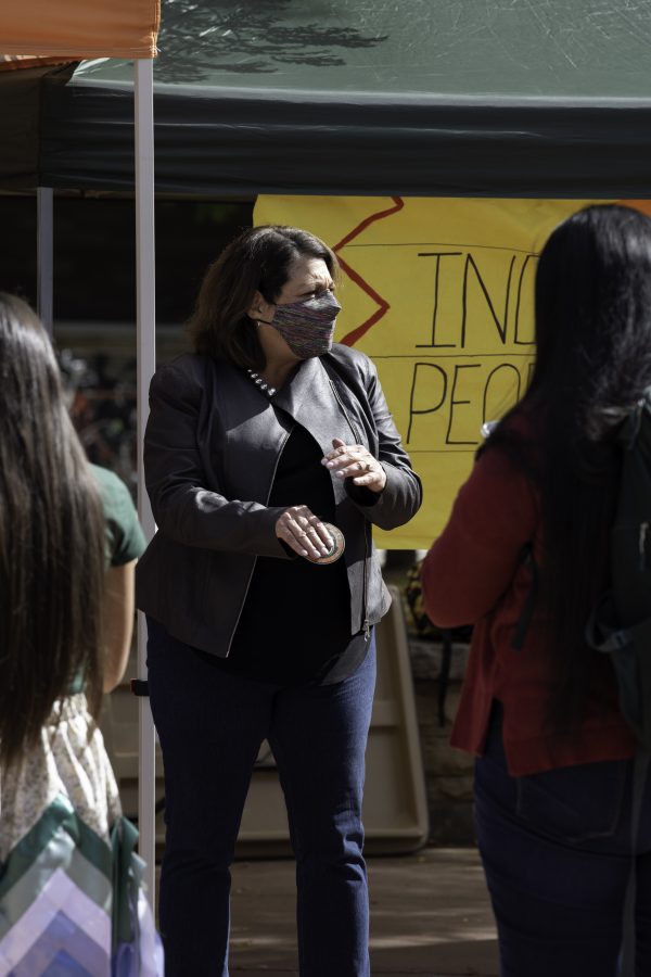 Joyce McConnell hands out Indigenous Peoples’ Day stickers to Colorado State University students on the Plaza Oct. 11. (Garrett Mogel | The Collegian)