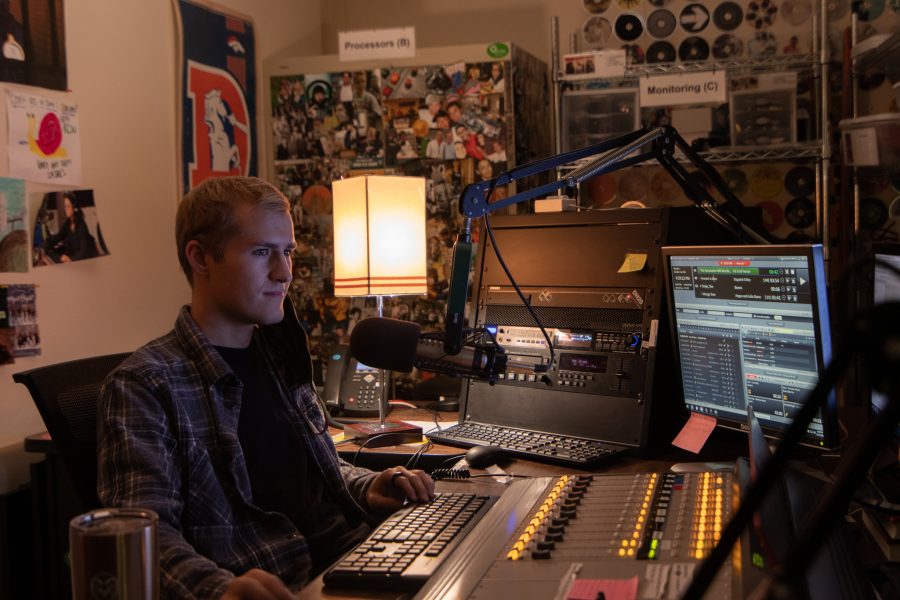Ben Haney, assistant podcast director at Colorado State University, at his desk behind the DJ Booth under Lory Student Center Oct 11. Haney stated, “I have like nine other people who I ended up training during the last couple weeks that have completely different things that they want to do with their podcast, so that process is something that has made me excited to come into work.” (The Collegian | Grayson Reed)