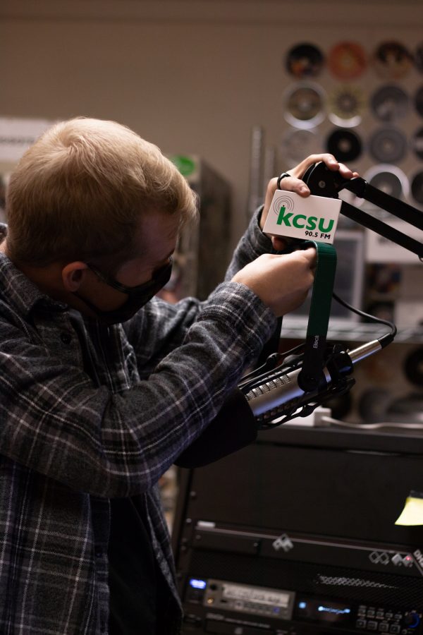 Ben Haney, assistant podcast director at Colorado State University, at his desk setting up a mic behind the DJ Booth under Lory Student Center Oct 11. When asked about Marie Tanksley Haney stated, “She’s in love with the format and she’ll talk about it for a long time which is so cool because I’ll learn a lot when I’m with her and it’s been so much more interesting to work with her because she’s so much more Knowledgeable.” (The Collegian | Grayson Reed)