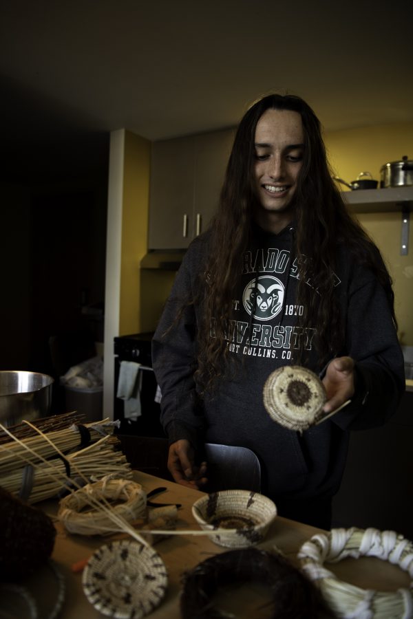 Stephen Young of the Mountain Maidu tribe in his apartment on Colorado State University campus Oct. 12, holding a hand-woven, human ribcage-patterned basket designed for his osteology class. Young is the first in five or more generations of his family to make woven baskets. “I’m starting to have to create patterns so that I could pass them on,” Young said. (Garrett Mogel | The Collegian)