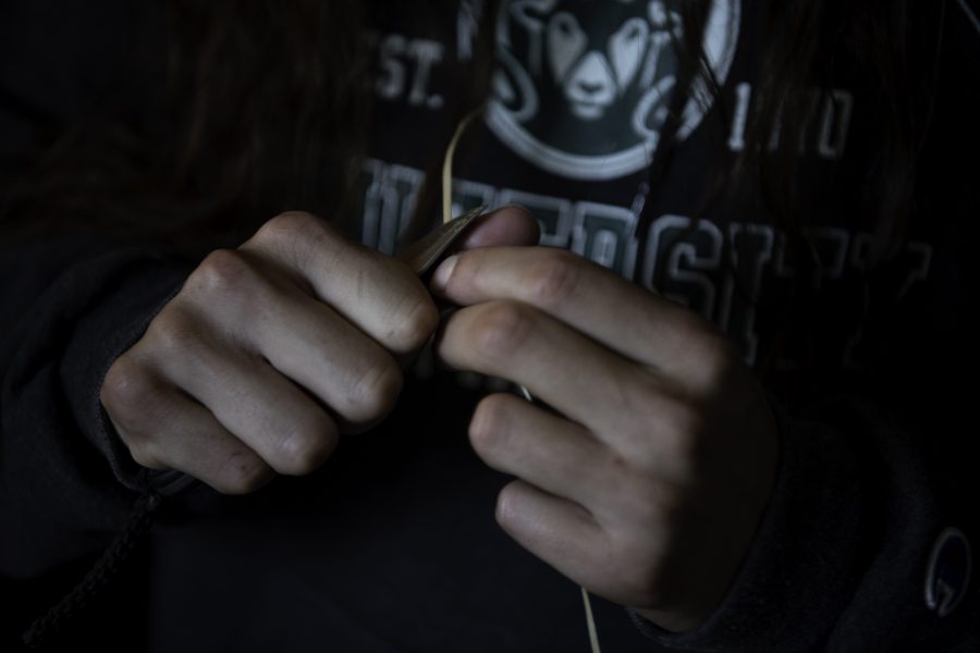 Stephen Young of the Mountain Maidu tribe scrapes down peeled California Red Bud to a uniform width before weaving with it. The wood is soaked in water before working with it. Young stated, “while it was a traditional job the weavers have fun doing this, so I don’t always pay attention to how long it takes.” Oct. 12. (Garrett Mogel | The Collegian)