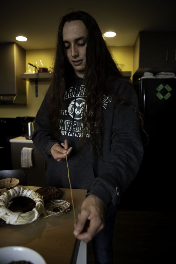 Stephen Young of the Mountain Maidu tribe measures out a strand of California Red Bud for a hand-woven basket in his apartment on Colorado State University campus. Young is the first in five or more generations of his family to weave basketry, learning for the past two years from tribal masters as well as on his own. Young stated “Basketry is the representation of our culture.” Oct. 12. (Garrett Mogel | The Collegian)