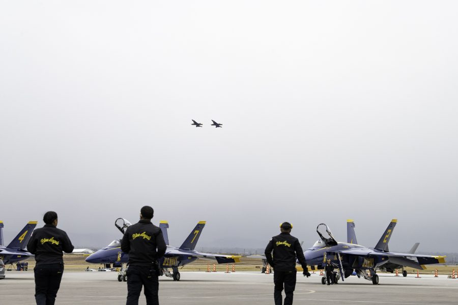 Three ground crew members for the United States Navy Blue Angels walk across the Northern Colorado Regional Airport ramp to the F/A-18 Super Hornets getting prepared for practice Oct. 14. The Blue Angels were preparing for the Great Colorado Air Show Oct. 14. (Garrett Mogel | The Collegian)