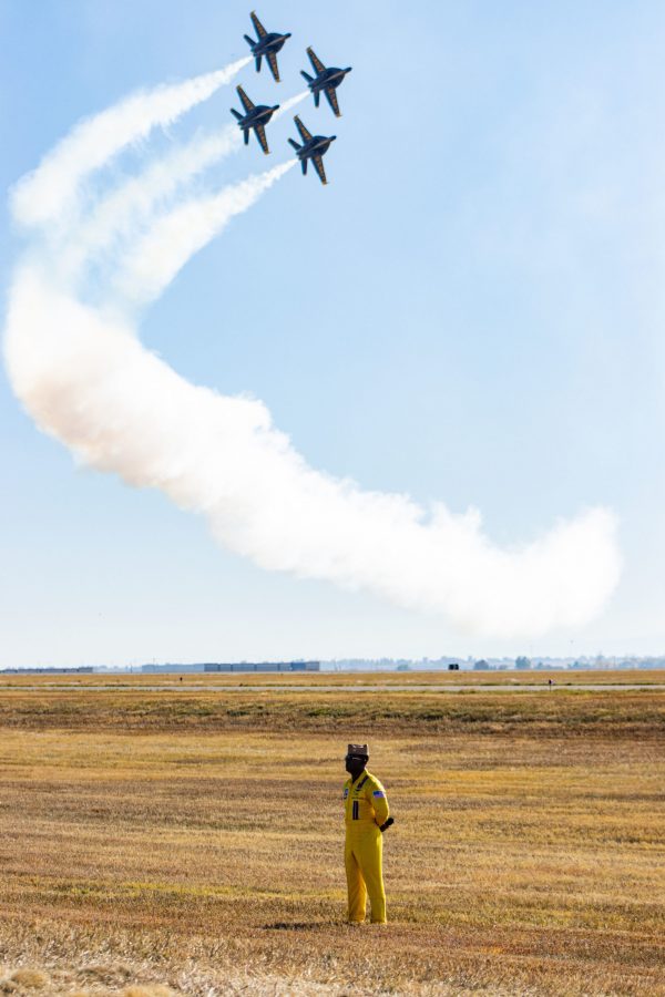 Lieutenant Commander Julius Bratton stands and jets fly behind him