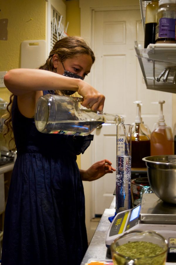 Sarah Josey, owner of Golden Poppy Herbal Apothecary measures water for a tincture