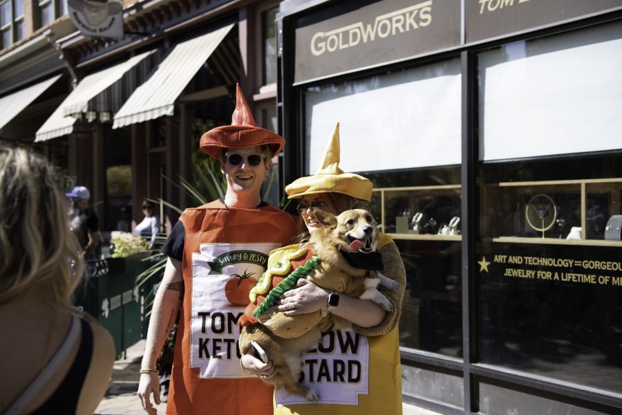 Otis is held by his owners Kelli and Andrew Silverstein who are dressed in condiment costumes for the Tour De Corgi parade through Old Town Fort Collins Colorado Oct. 2. (Garrett Mogel | The Collegian)
